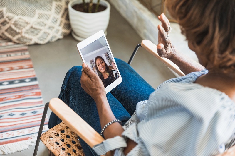 grandmother waving at her granddaughter on a video call