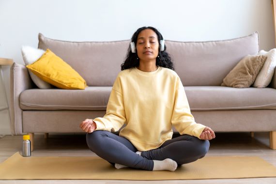 photo of a woman sitting on the floor with headphones on meditating