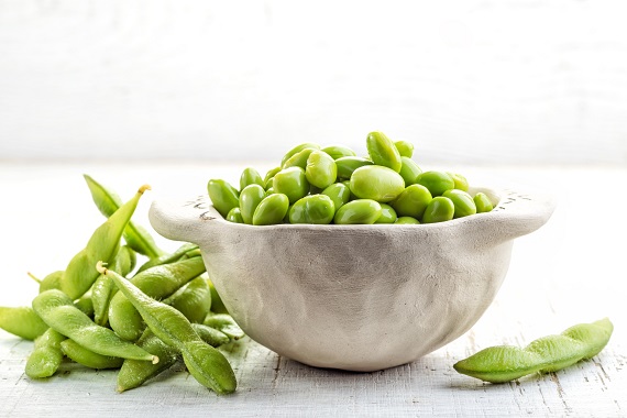 bowl of edamame on a table with edamame next to the bowl