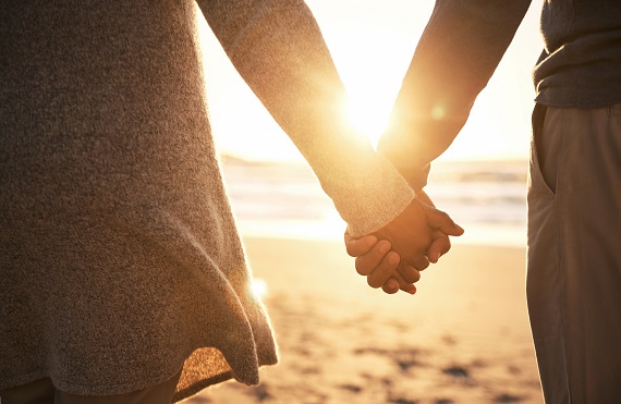 Couple holding hands on the beach at sunset