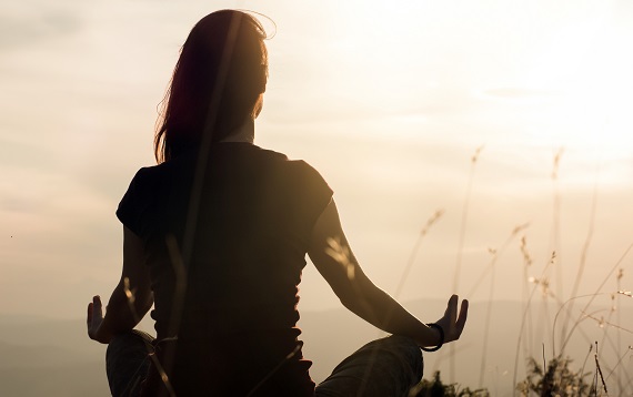 photo of woman sitting in a lotus position near a body of water 