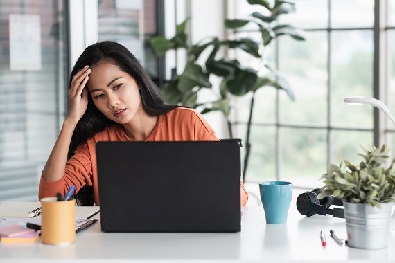 woman sitting in front of laptop looking stressed out