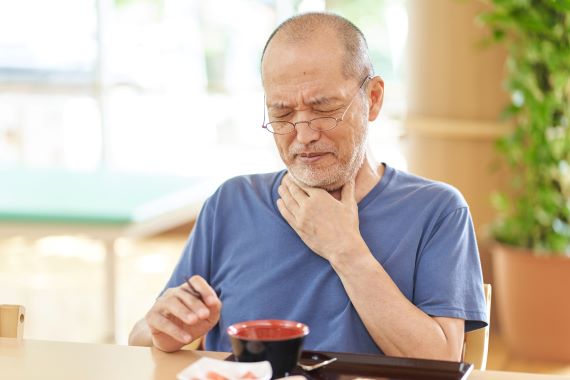 photo of a man with his hand on his throat with an expression of discomfort