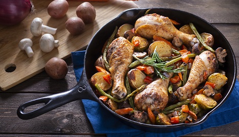 cast iron skillet with roasted chicken drumsticks, vegetables and rosemary