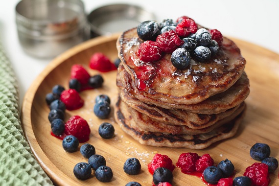 stack of whole wheat pancakes with blueberries and raspberries