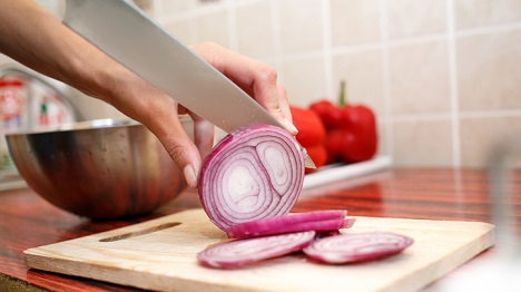 Chef cutting an onion on a table.