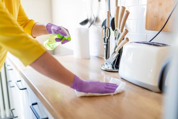 photo of person wearing gloves and cleaning kitchen counters