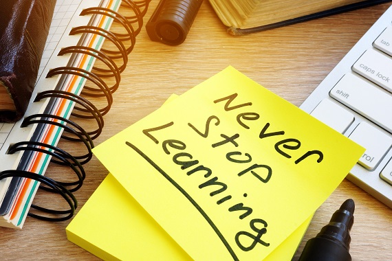 yellow sticky note on a desk that says never stop learning