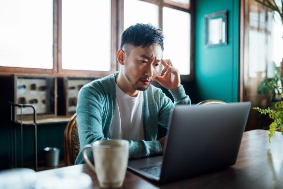 man looking at laptop with a frustrated expression on his face