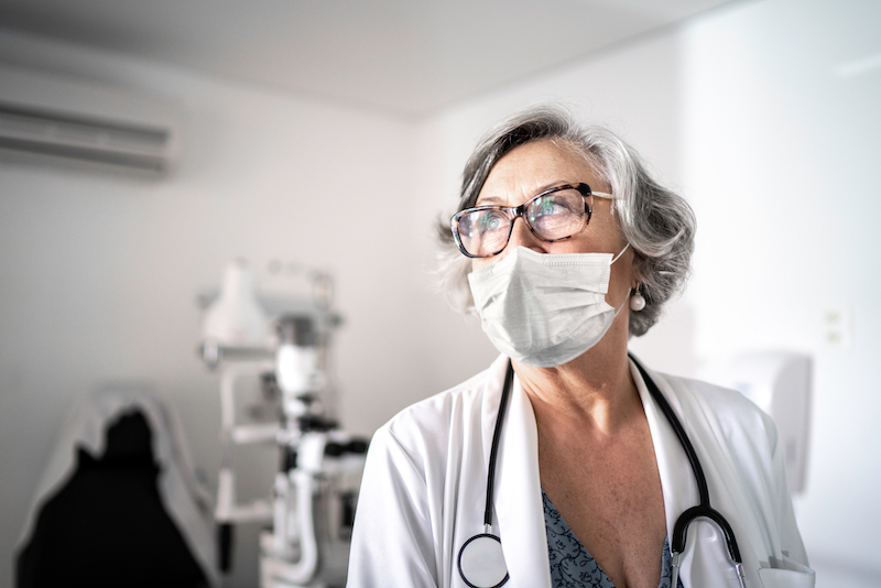 A masked doctor works in her office.