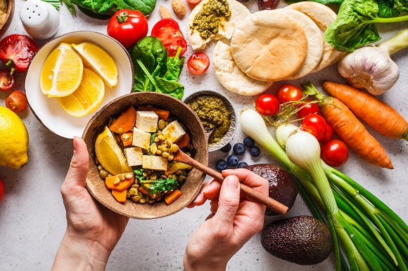 Bowl of salad with tofu on a table full of vegetables