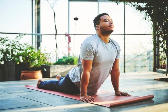 photo of man practicing yoga sun salutations