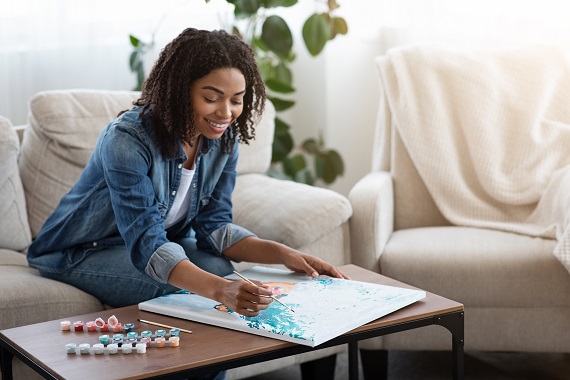 woman painting a canvas on her coffee table