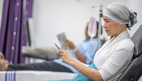 woman looking at smartphone during chemotherapy infusion