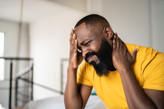 man in pain touching his head and neck