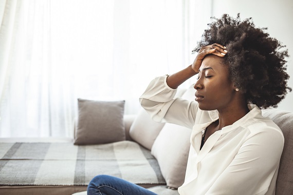 woman sitting in a chair with her hand on her forehead looking overwhelmed