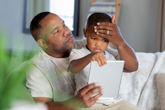 father holding his young son and checking for a fever