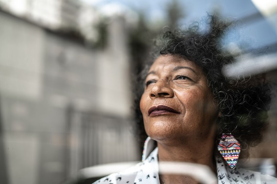 woman looking out a window, looking hopeful