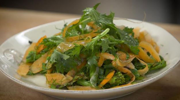 A warm salad of greens on a plate.