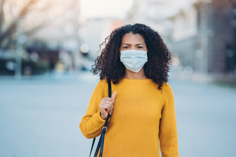 A woman wears a mask while out in the city. 